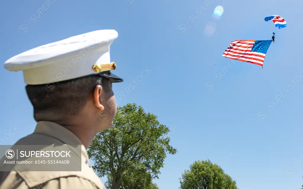 U.S. Marine Corps Capt. Anthony B. Reyes, the communication strategy and operations director assigned to the 15th Marine Expeditionary Unit, Task Force Los Angeles, observes an American flag attached to a parachutist man during a Memorial Day ceremony at Green Hills Memorial Park in Rancho Palos Verdes, California, as part of Los Angeles Fleet Week, May 30, 2022. The purpose of Fleet Week is to showcase the capabilities of the Navy-Marine Corps team and give back to the community with events, static displays, and personal interactions between service members and the public.