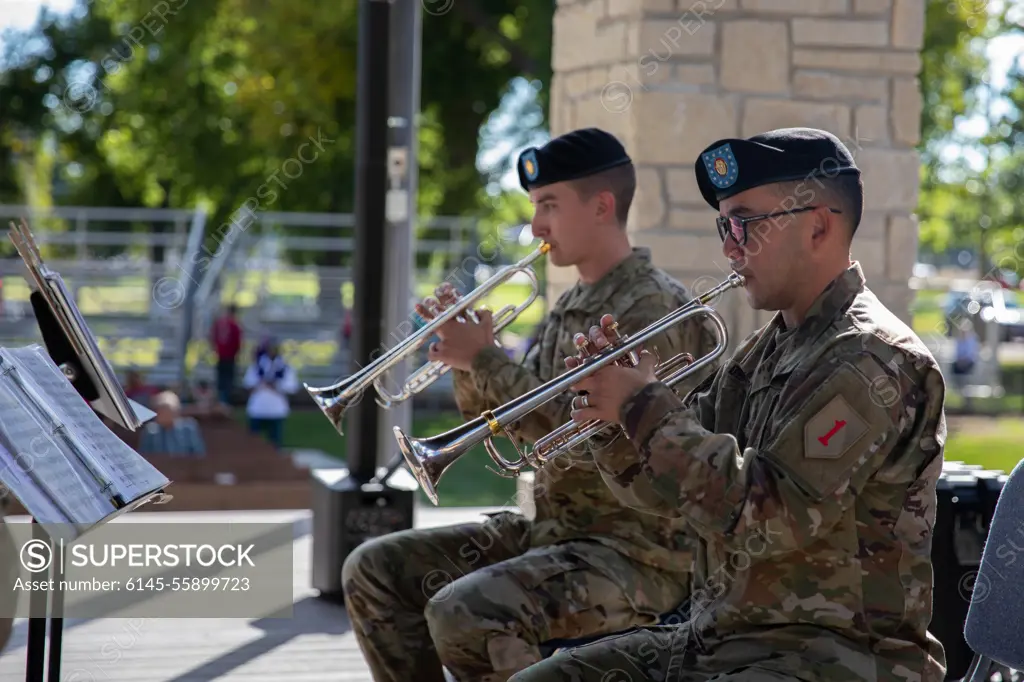 Sgt. Ethan Berkebile (left), and 1st Sgt. Larry Dean (right), Soldiers with the 1st Infantry Division Band, play the trumpet September 11, 2022, at the city park in Manhattan, Kansas. the 1ID Band was performing during a Day of Remembrance event hosted by the city.