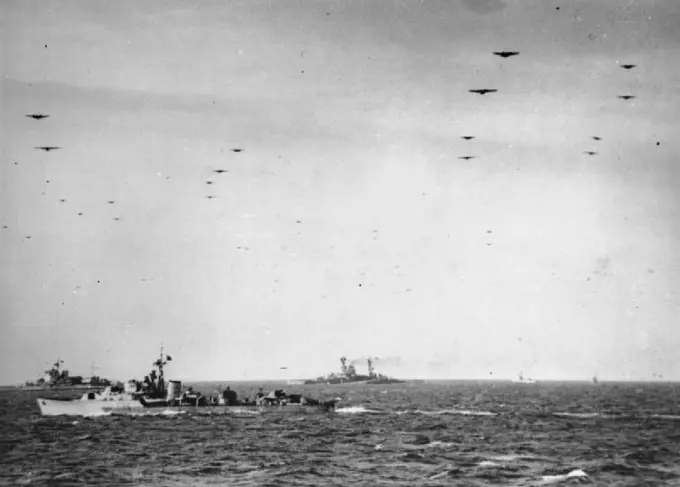 The Royal Navy during the Second World War- Operation Overlord (the Normandy Landings)- D-day 6 June 1944 Glider borne troops passing over units of the Royal Navy on their way to the invasion beaches of Normandy. In the background are the battleships HMS WARSPITE and HMS RAMILLIES whilst an unidentified destroyer sails in the middle distance. Photograph taken from the cruiser FROBISHER, which had helped bombard the enemy coastal positions during the week before D-Day.