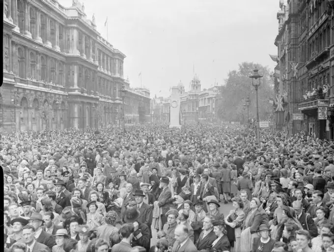 Ve Day Celebrations in London, England, UK, 8 May 1945 Huge crowds of people are gathered in Whitehall to listen to Churchill's Victory speech and to celebrate Victory in Europe Day. The crowd is a mix of service personnel, civilians and children. Behind them can be seen the Cenotaph. People line the balconies of the buildings on the right hand side of the road. This photograph was taken from the Parliament Square end of Whitehall, looking past the Cenotaph towards Trafalgar Square.