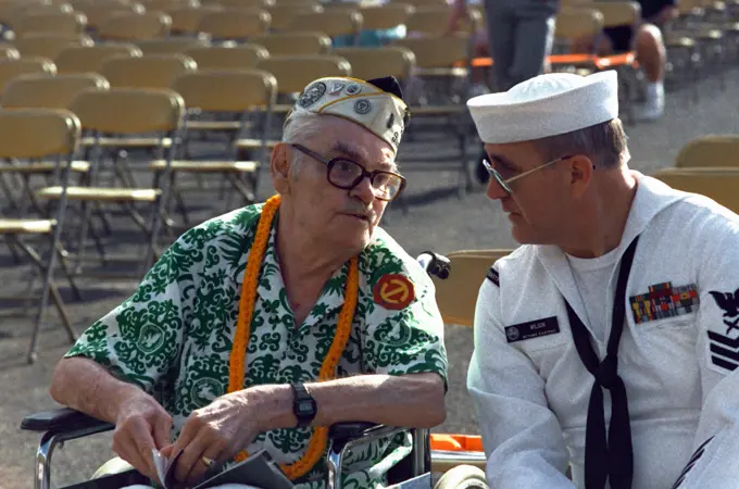 Cryptologic Technician 1ST Class F. Scott Wilson sits beside Raymond Sandlin prior to the start of the Hawaii Remembrance Day observation marking the 50th anniversary of the Japanese attack on Pearl Harbor. Sandlin was an Army private stationed at Hickam Air Field on December 7, 1941. Base: Naval Station, Pearl Harbor State: Hawaii(HI) Country: United States Of America (USA)