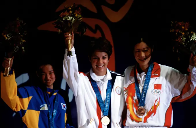 Nancy Johnson, of the US, raises her hands with Cho-Hyun Kang of South Korea (Left), and Jing Gao of China (Right), during the medal ceremony in which Johnson won the gold medal followed by Kang and Goa in the Women's 10-Meter Air Rifle Competition at the 2000 Olympic games in Sydney, Australia. Base: Sydney State: New South Wales Country: Australia (AUS)