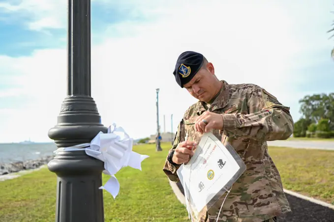 U.S. Air Force Master Sgt. Steven Koster, 6th Security Forces Squadron noncommissioned officer in charge of readiness, places a sign with a fallen veteran during the Second Annual Memorial Day Remembrance event at MacDill Air Force Base, Florida, May 25, 2022. Over 75 signs and ribbons were placed to honor fallen service members