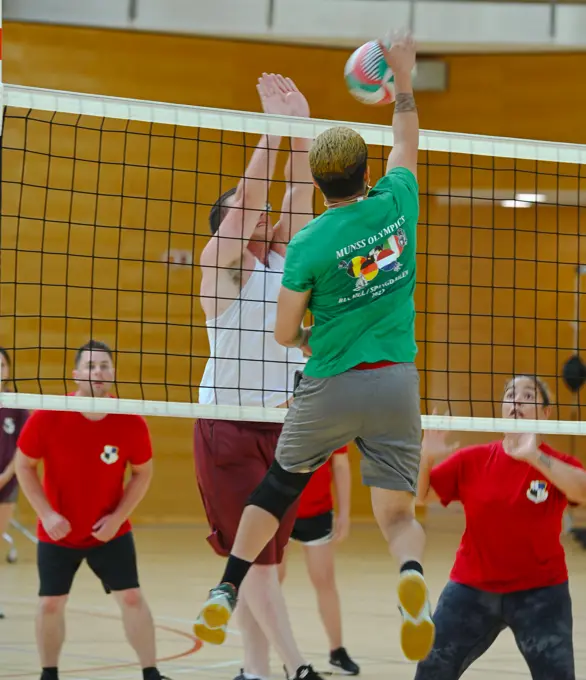 Airmen from the 702nd Munitions Support Squadron (in green) compete against Airmen from the 703rd MUNSS in a volleyball game during the 2022 MUNSS Olympics at Spangdahlem Air Base, Germany, August 5, 2022. Members of the MUNSS sites competed in various activities including soccer, kickball, flag football, powerlifting, running and volleyball. This is the first MUSSS Olympics held since 2019. It is designed for MUNSS personnel to network and create face-to-face relationships, which enhances mission success.