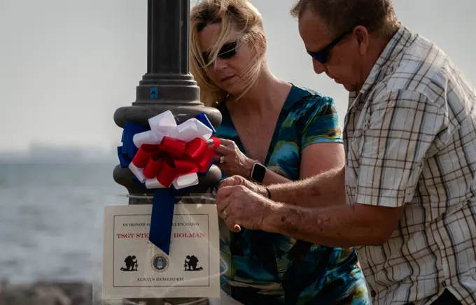 Debra and Gary Holman, surviving family of Tech. Sgt. Steven Holman, place amemorial sign for their son on a lamp post at MacDill Air Force Base,Florida during the Second Annual Memorial Day Remembrance event May 25,2022. Volunteers from MacDill AFB and the surrounding community cametogether to place 75 signs around MacDill to honor fallen service members.