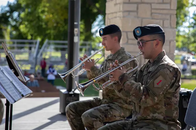 Sgt. Ethan Berkebile (left), and 1st Sgt. Larry Dean (right), Soldiers with the 1st Infantry Division Band, play the trumpet September 11, 2022, at the city park in Manhattan, Kansas. the 1ID Band was performing during a Day of Remembrance event hosted by the city.