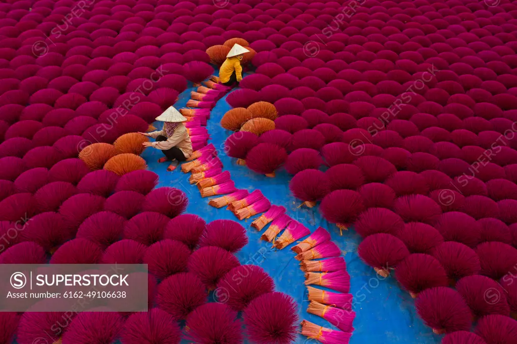 Aerial view of incense workers sits surrounded by thousands of incense sticks, where the sticks have been traditionally made for hundreds of years in Quang Phu Cau, Hanoi, Vietnam.