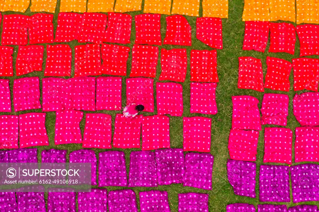 Aerial view of a woman working placing colourful towels in a field near Araihazar, Dhaka district, Bangladesh.