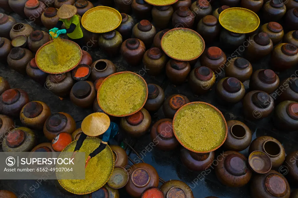 Aerial view of people working in a factory processing Soya source mixing with yellow rice in barrels, Huyện Mỹ Hào, Hung Yen province, Vietnam.