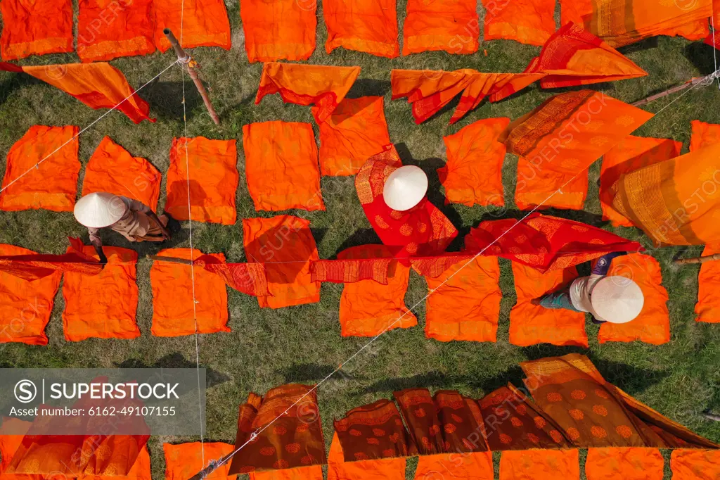 Aerial view of woman working in a public laundry drying red cloth in Araihazar, Dhaka, Bangladesh.