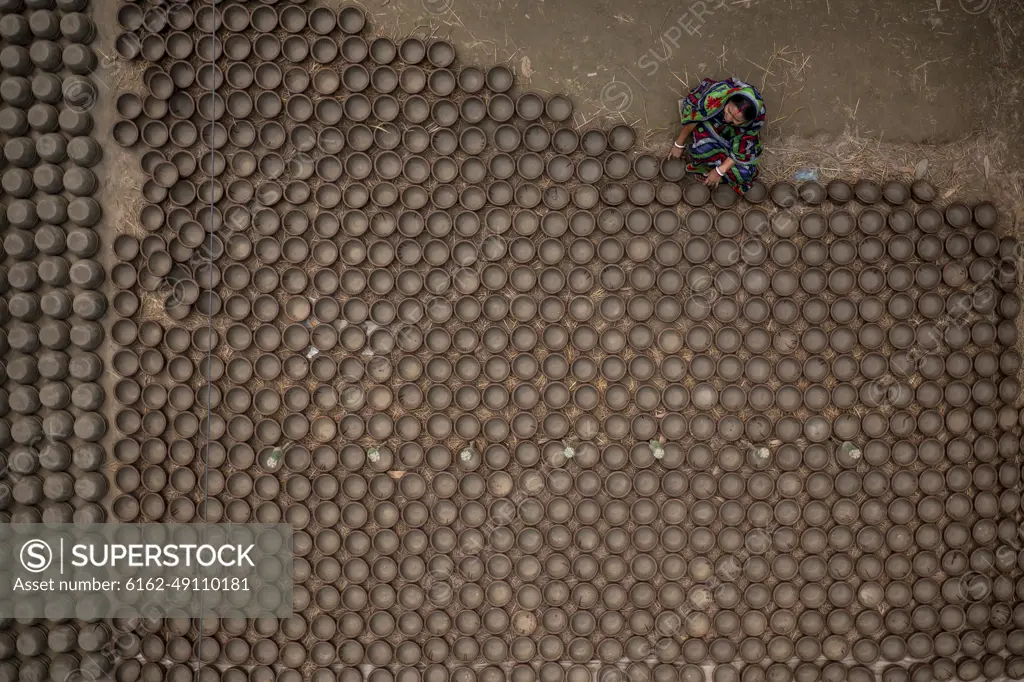 Manikgonj, Bangladesh - 20 February 2022: Aerial view of a woman working with clay pot in Manikgonj, Dhaka, Bangladesh.