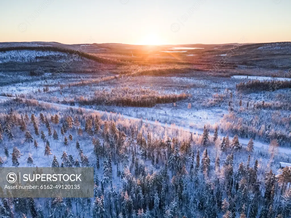 Aerial view of sun rising above winter landscape in Norrbotten, Sweden.