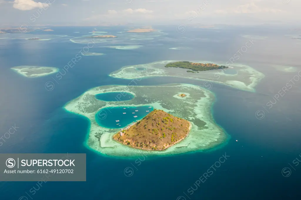 Aerial view of Pulau Kukusan island and its archipelagos with golden paradise beaches, East Nusa Tenggara, Indonesia.