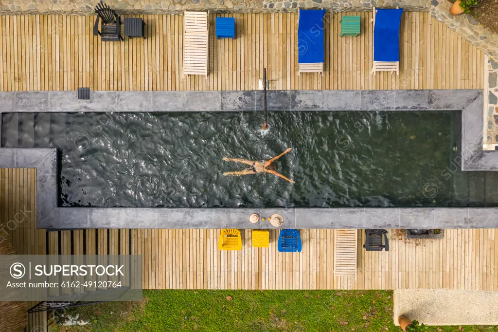 Salgar, Colombia - 26 February 2020: Aerial view of a woman swimming in a pool with a black swim suit in a luxury resort, Salgar, Antioquia, Colombia.