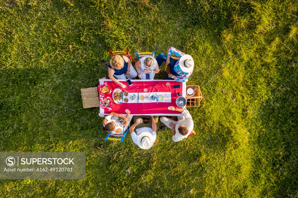 Salgar, Colombia - 29 February 2020: Aerial view of a group of friends having a toast while eating on a hilltop with a beautiful landscape in background, Antioquia, Colombia.