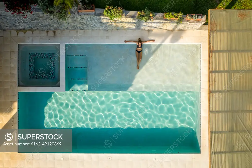 Salgar, Colombia - 26 February 2020: Aerial view of a woman with black swim suit relaxing on the swimming pool of a luxury hotel, Antioquia, Colombia.