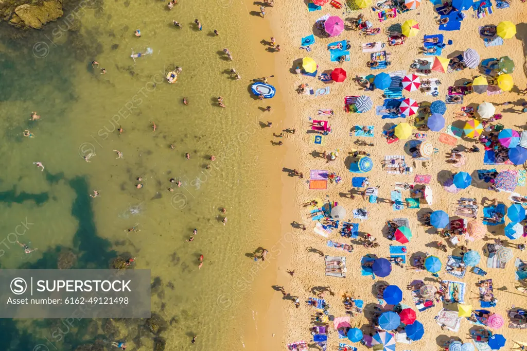 Aerial view above of people enjoying the summer at Praia do Camilo, Portugal.