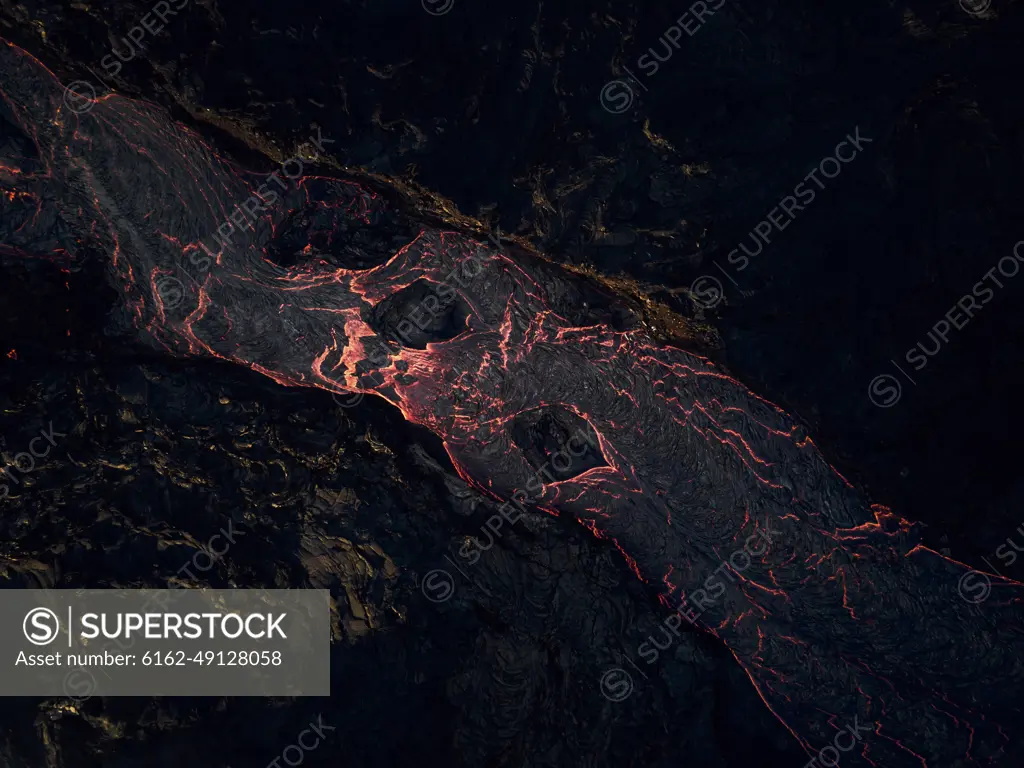 Aerial view of lava streaming down the mountain ridge, view of a river of lava flowing from the craters in Grindavík, Southern Peninsula, Iceland.