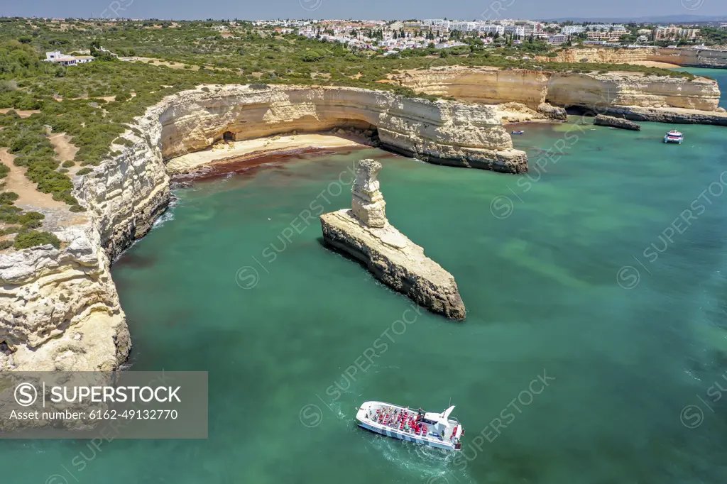 Portugal, Albufeira - 29 May 2021: Aerial view of the rocky coastline and coves with a boat on the turquoise waters of Albufeira, Algarve, Portugal.