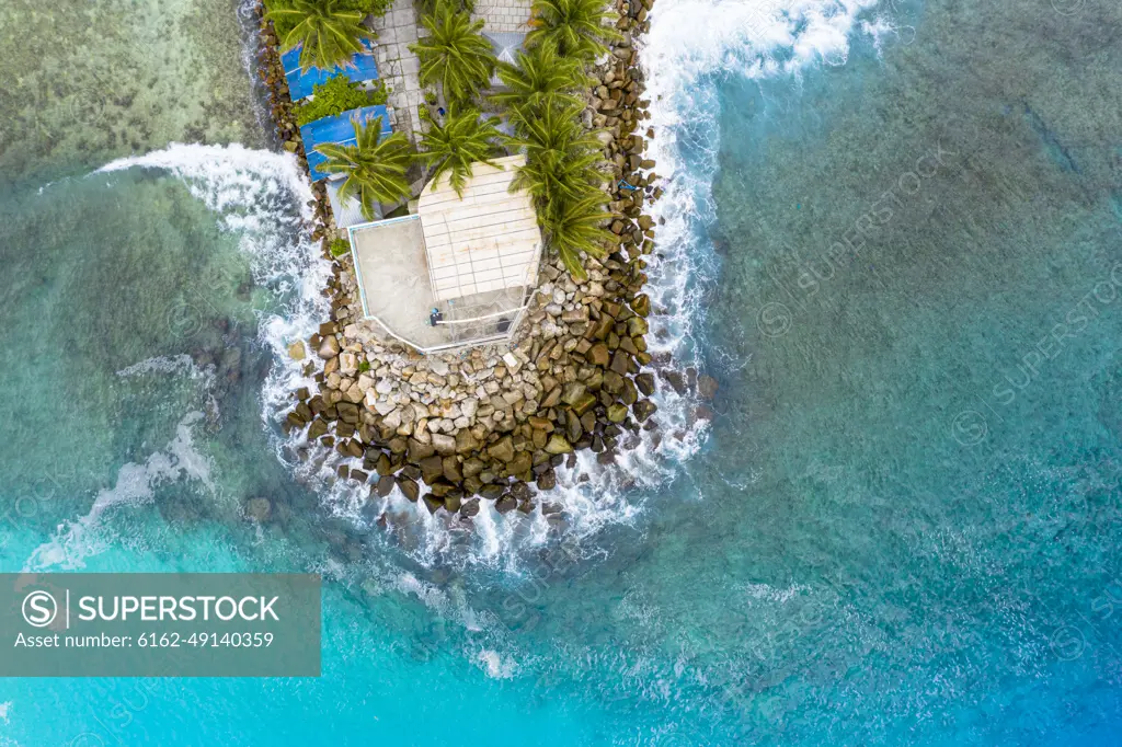 Aerial view of a house in the harbour, with waves breaking, Maldives.