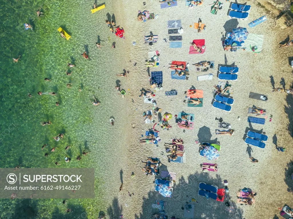 Aerial view of people relaxing at Gortanova beach, a narrow inlet with turquoise water, Pula, Istria, Croatia.