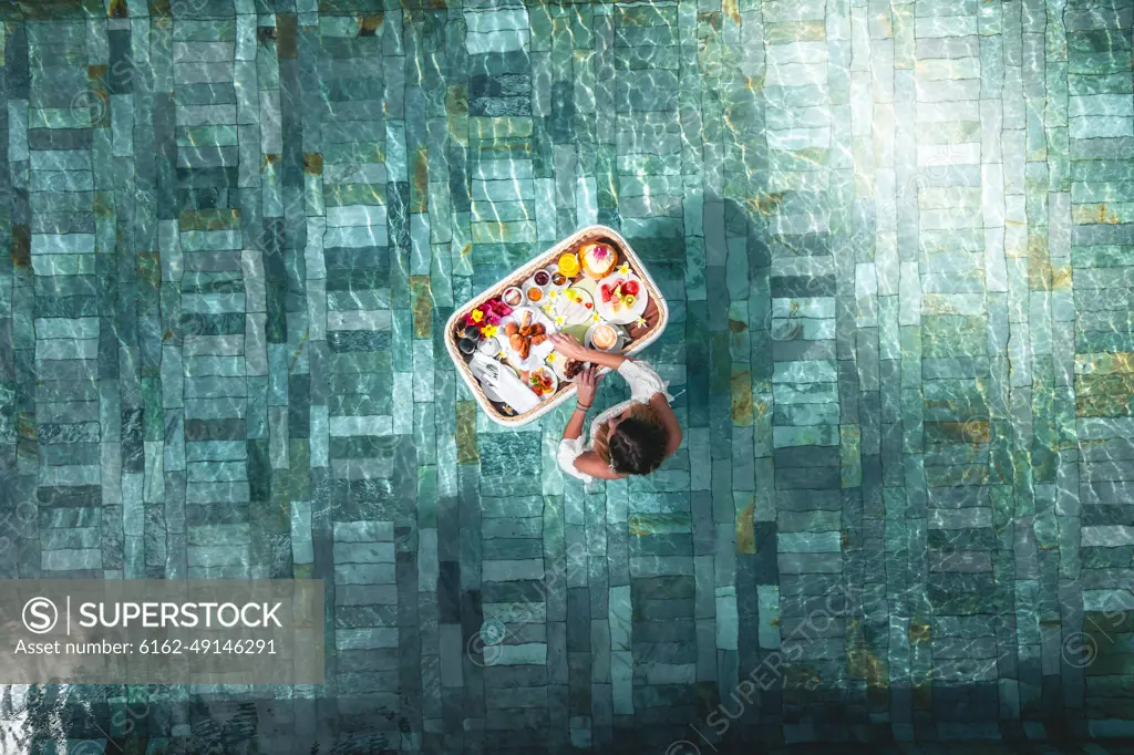 Aerial view of a woman having a floating breakfast in a swimming pool of a luxury resort, Ilot Lievres, Trou d'Eau Douce, Flacq district, Mauritius.