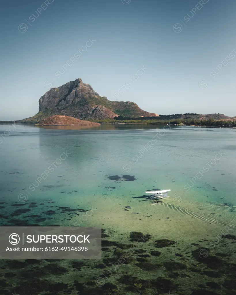 Aerial view of a water airplane landing in a lagoon with barrier reef with Le Morne Mountain in background, Le Morne Brabant, Riviere Noire, Mauritius.