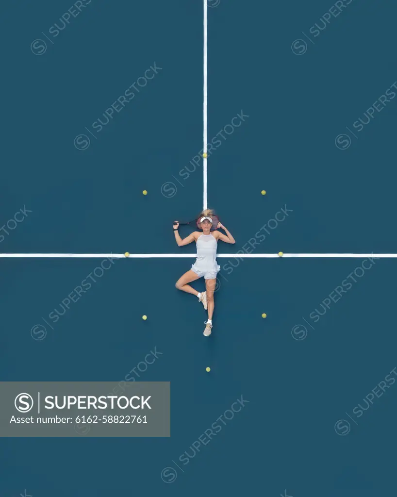 Aerial drone view of a female tennis player laying on a blue tennis court in Melbourne, Victoria, Australia.