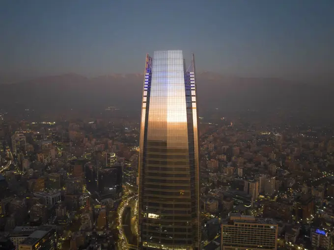 Aerial View Of Sunset Reflecting Off Tall Skyscraper With Cityscape And Andes Mountain Range In Distance, Santiago, Chile.