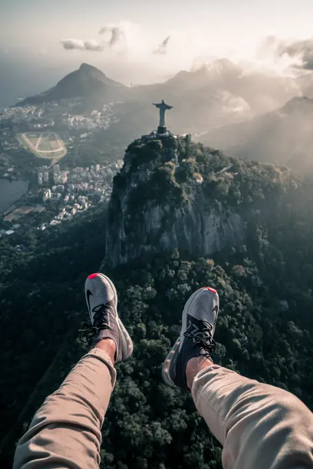 RIO DE JANEIRO, BRAZIL - 22 OCTOBER 2018: Aerial View From Helicopter Of Legs Hanging Out Over Christ The Redeemer Statue And Corcovado Mountain In City Of Rio De Janeiro, Brazil