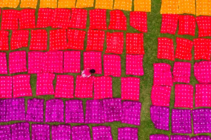 Aerial view of a woman working placing colourful towels in a field near Araihazar, Dhaka district, Bangladesh.