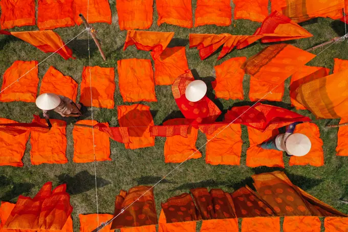 Aerial view of woman working in a public laundry drying red cloth in Araihazar, Dhaka, Bangladesh.