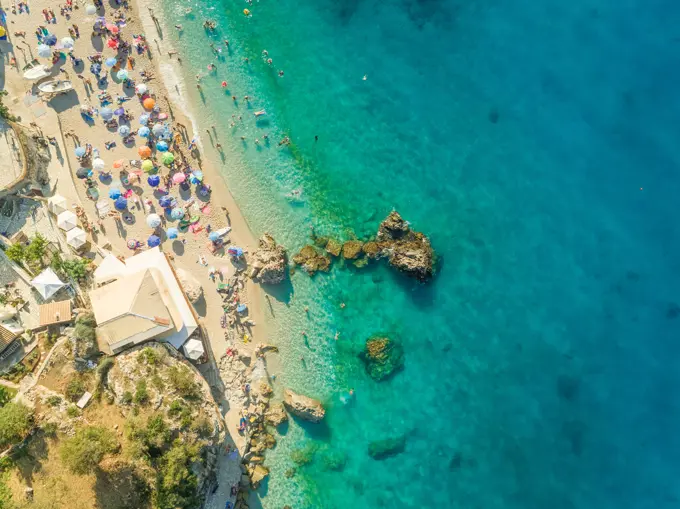 Aerial view of crowded beach with vacationers, parasols and resort, Lefkada, Greece.