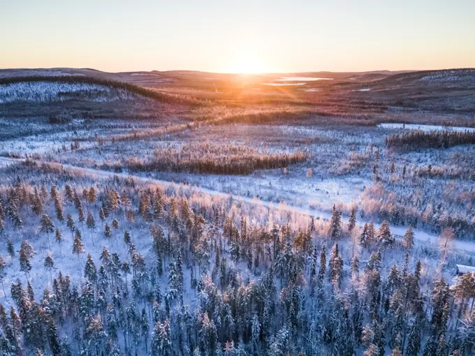 Aerial view of sun rising above winter landscape in Norrbotten, Sweden.