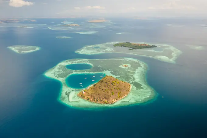 Aerial view of Pulau Kukusan island and its archipelagos with golden paradise beaches, East Nusa Tenggara, Indonesia.