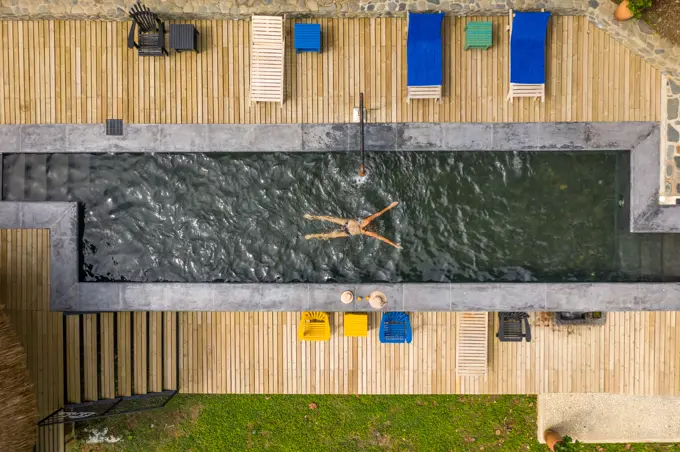 Salgar, Colombia - 26 February 2020: Aerial view of a woman swimming in a pool with a black swim suit in a luxury resort, Salgar, Antioquia, Colombia.