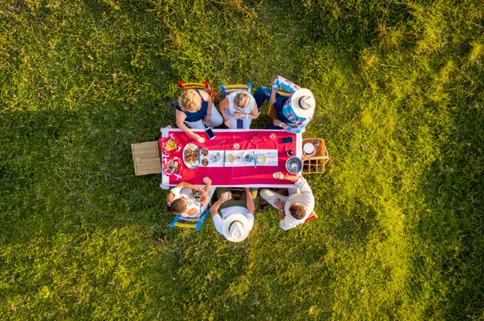 Salgar, Colombia - 29 February 2020: Aerial view of a group of friends having a toast while eating on a hilltop with a beautiful landscape in background, Antioquia, Colombia.