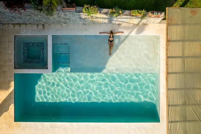 Salgar, Colombia - 26 February 2020: Aerial view of a woman with black swim suit relaxing on the swimming pool of a luxury hotel, Antioquia, Colombia.