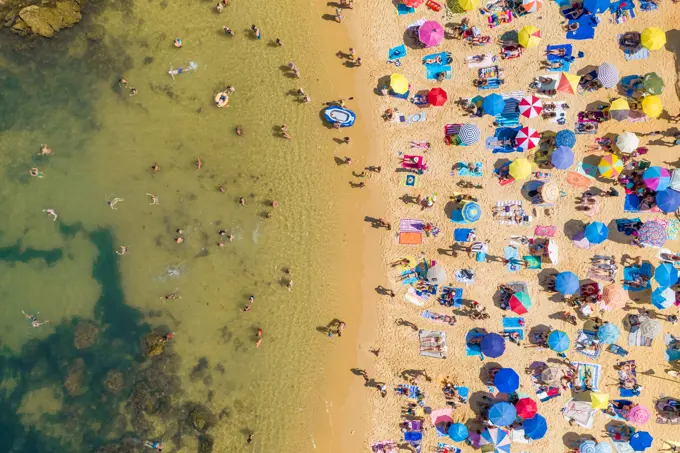 Aerial view above of people enjoying the summer at Praia do Camilo, Portugal.