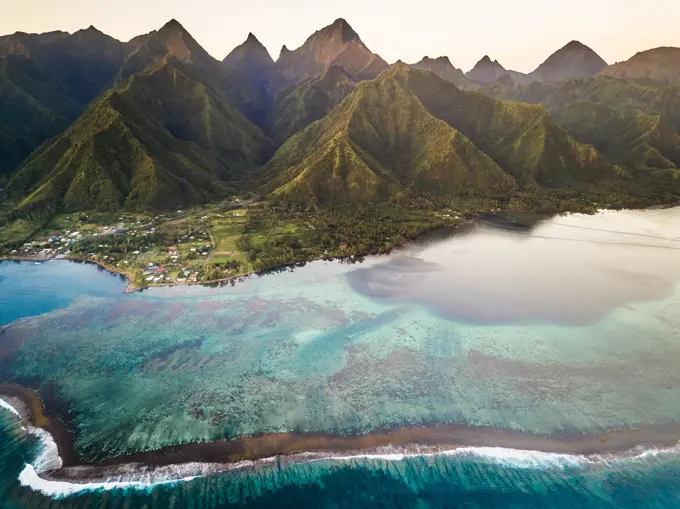 Aerial view of coral reef with The Mighty Mount Aorai in the background in Tahiti, French Polynesia.