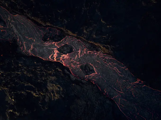 Aerial view of lava streaming down the mountain ridge, view of a river of lava flowing from the craters in Grindavík, Southern Peninsula, Iceland.