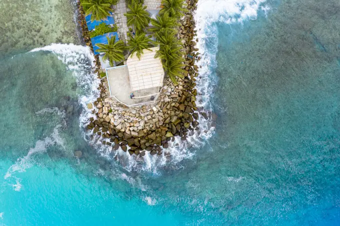 Aerial view of a house in the harbour, with waves breaking, Maldives.