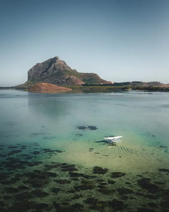 Aerial view of a water airplane landing in a lagoon with barrier reef with Le Morne Mountain in background, Le Morne Brabant, Riviere Noire, Mauritius.