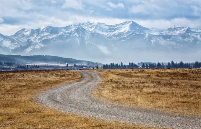 A winding path at the foothills of the Canadian Rockies leads to the majestic snow covered mountains in Alberta, Canada