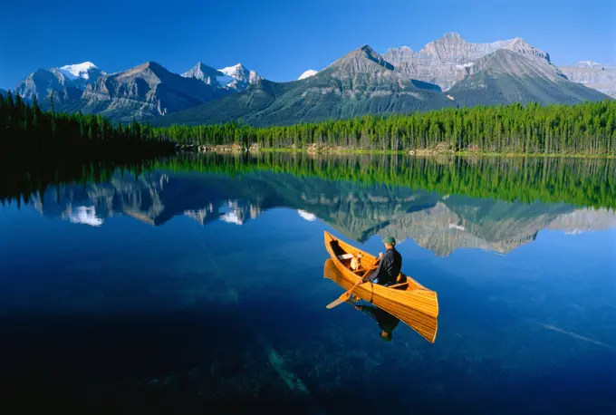 Man and dog in canoe in Herbert Lake, Banff National Park, Alberta, Canada