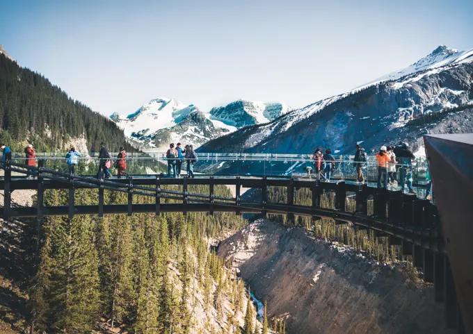 Tourists admiring the panorama while walking on the glass floor at Glacier Skywalk, Icefields Parkway, Alberta, Canada