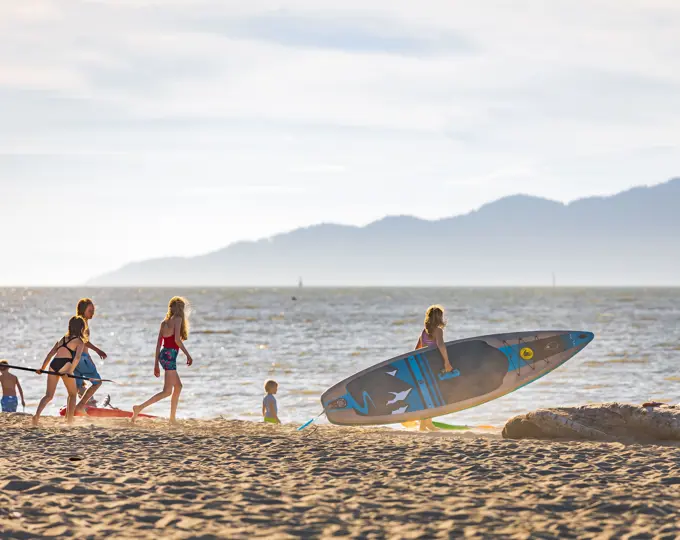 Happy children with SUP at the beach on vacation. Active family riding SUP boards and paddling in the ocean on a beautiful sunset-July 24,2022-Vancouv