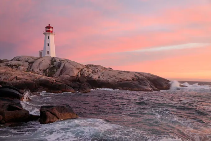 Peggys Cove Lighthouse illuminated at dusk with reflection in water, Nova Scotia, Canada