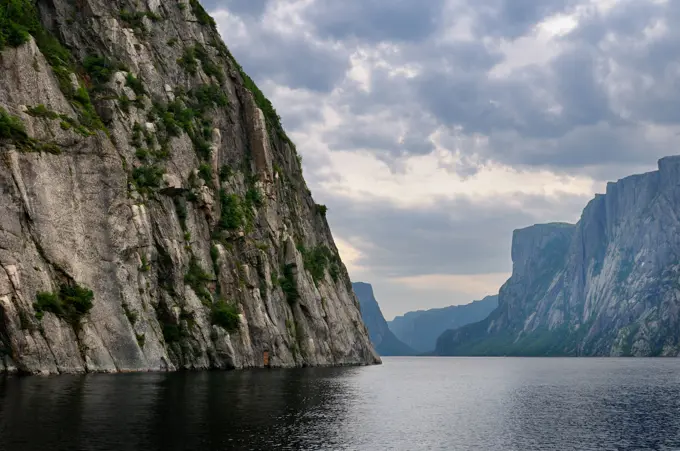 Clouds over steep Igneous rock wall at Western Brook Pond inland fjord at Gros Morne National Park Newfoundland