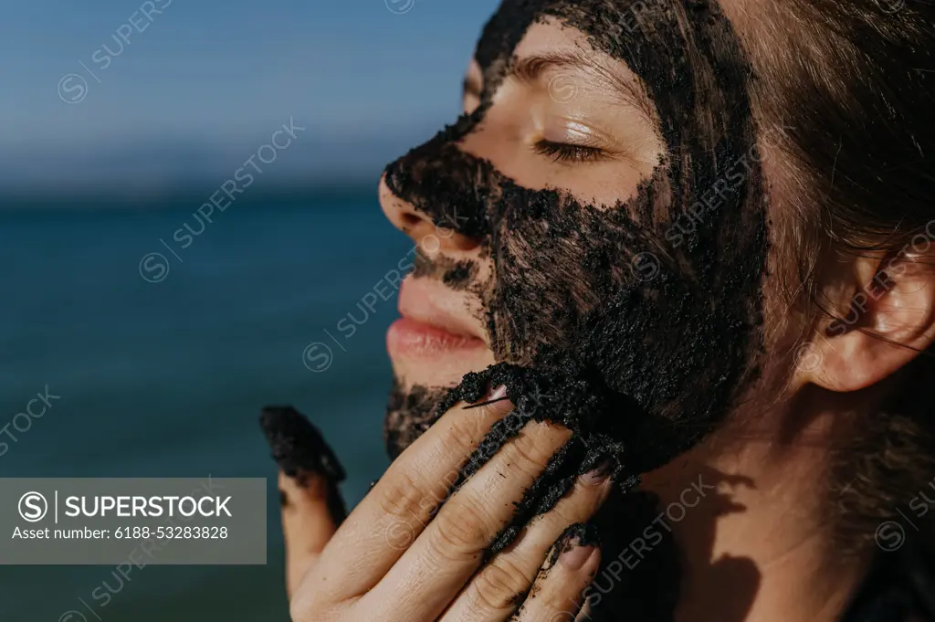 Woman applies healing mud to her face and body. Natural healing mud in Croatia on the beach. Woman applies healing mud to her face and body. Natural healing mud in Croatia on the beach. Therapeutic mud or peloids rich in minerals and organic substances. model released